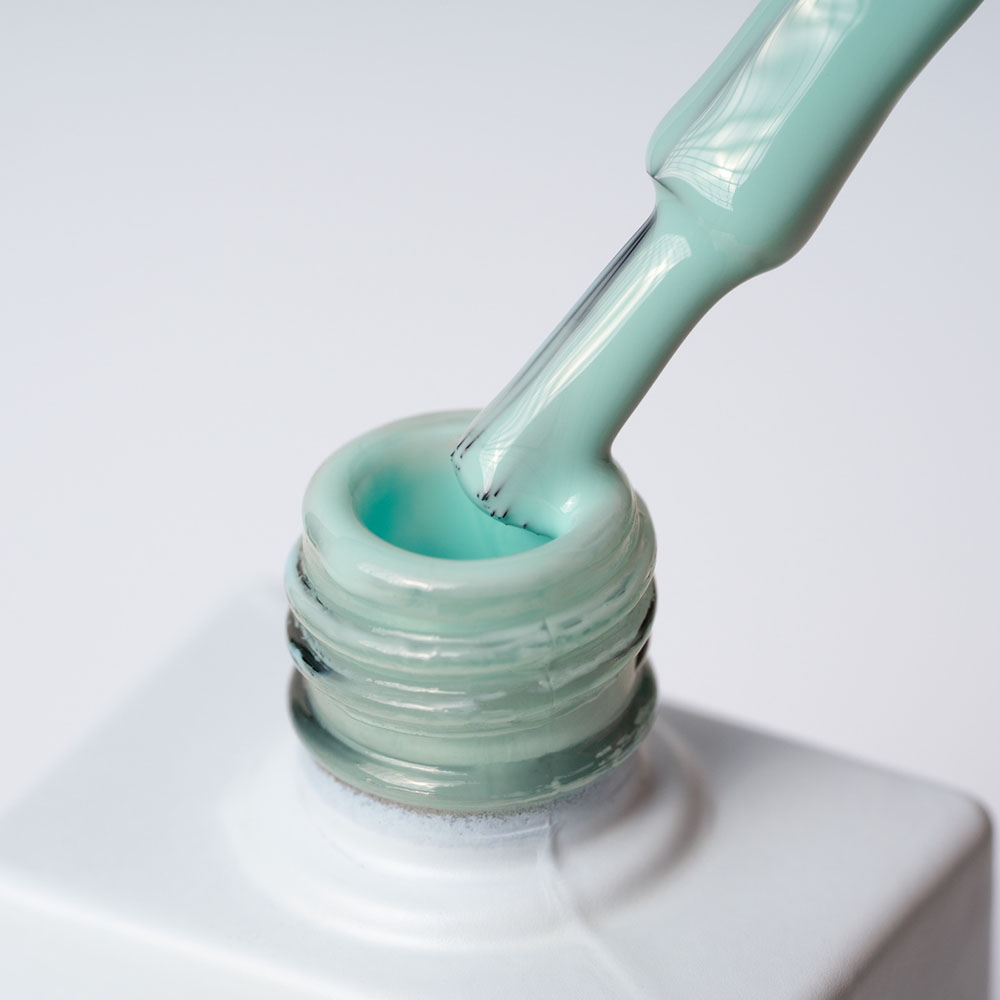 Lakier hybrydowy No 009 – Miętowy na pędzelku Lakier hybrydowy No. 009 - w odcieniu miętowym - pędzelek zanurzony w lakierze
