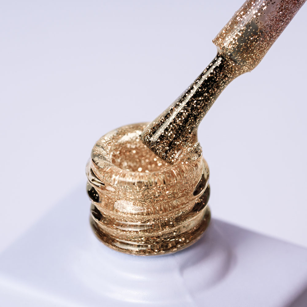 Lakier hybrydowy No. 073 - w odcieniu złoty brokatowy - pędzelek zanurzony w lakierze