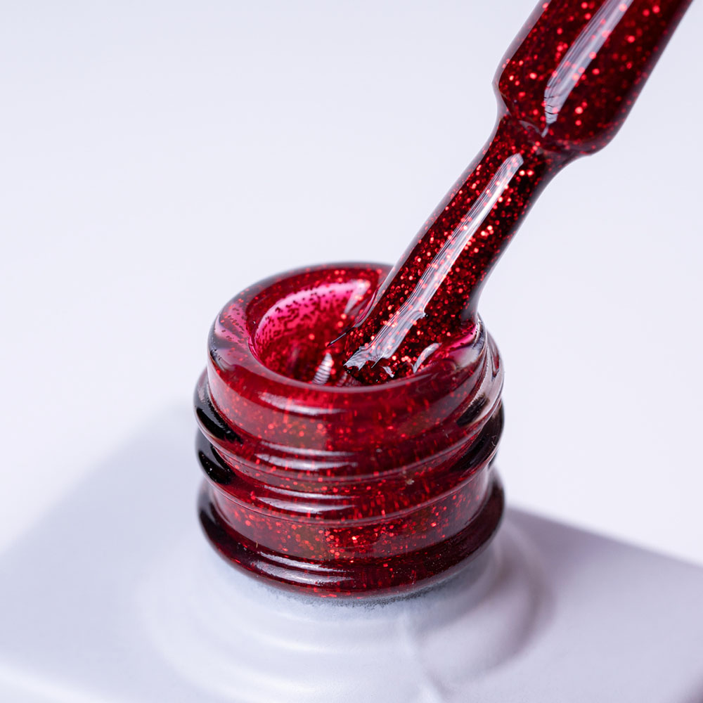 Lakier hybrydowy No 100 - w odcieniu czerwony brokatowy - pędzelek zanurzony w lakierze