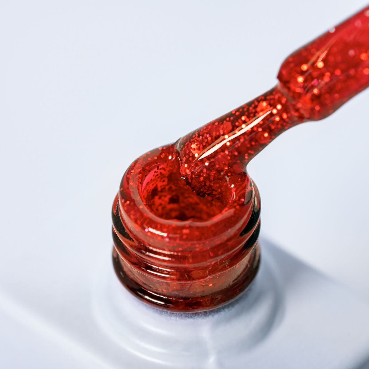 Lakier hybrydowy No. 139 - intensywna czerwień z brokatem - pędzelek zanurzony w lakierze