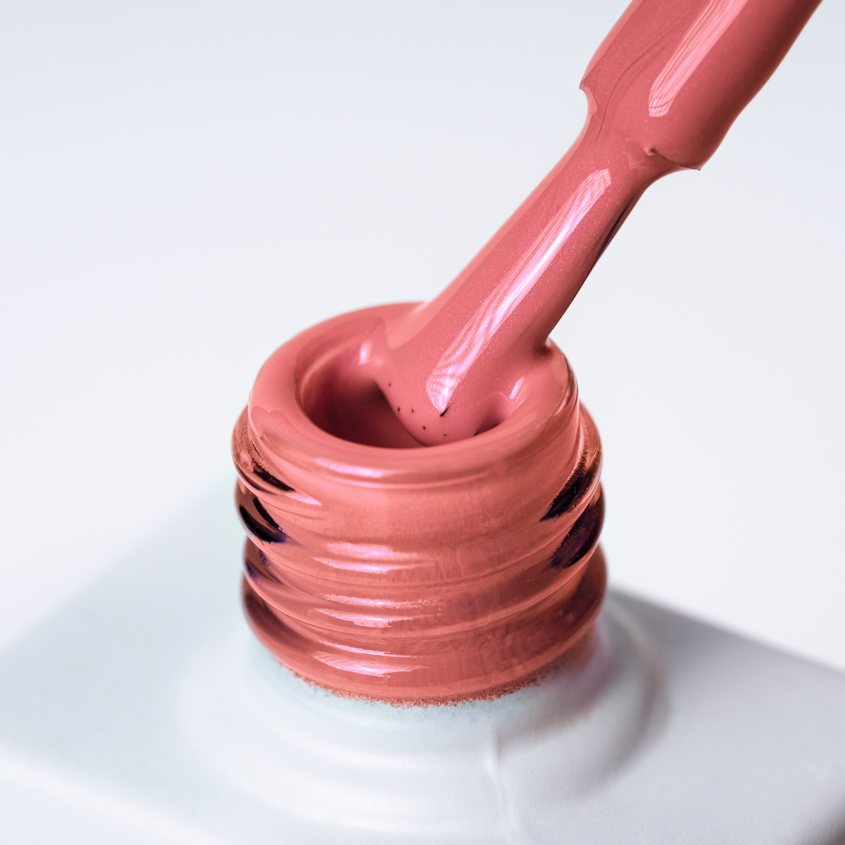 Lakier hybrydowy No. 147 - w odcieniu koralowym z drobinkami - pędzelek zanurzony w lakierze